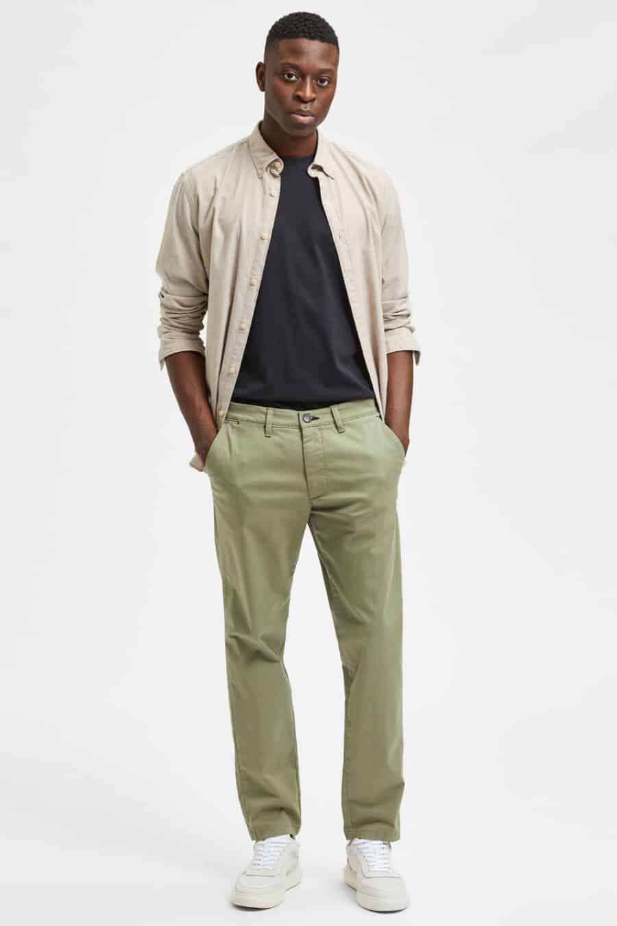 Men's light grene chino pants, navy T-shirt, light brown Oxford shirt and off-white sneakers outfit