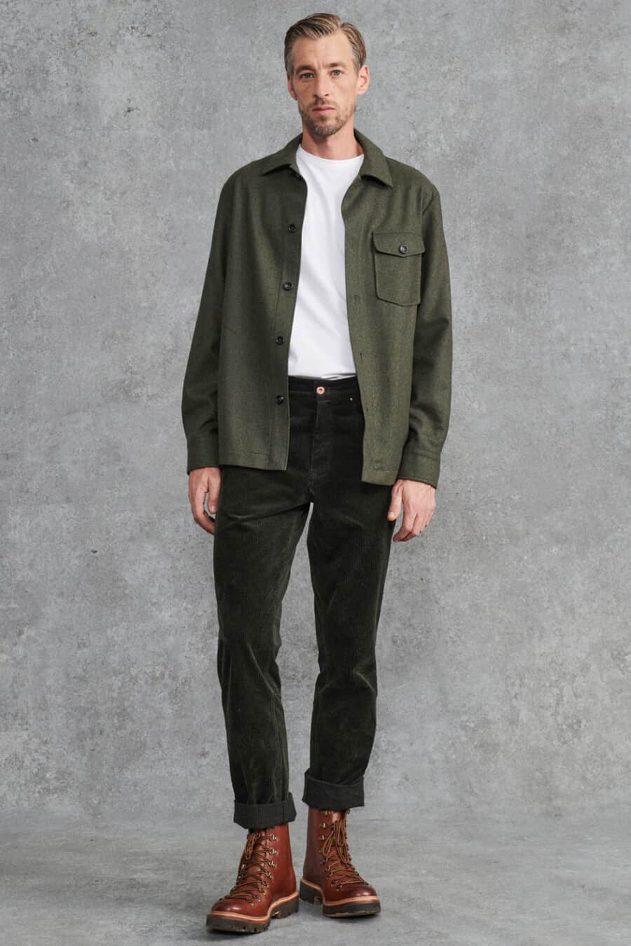 Men's green corduroy pants, tucked in white T-shirt, open green flannel overshirt and brown leather military boots outfit