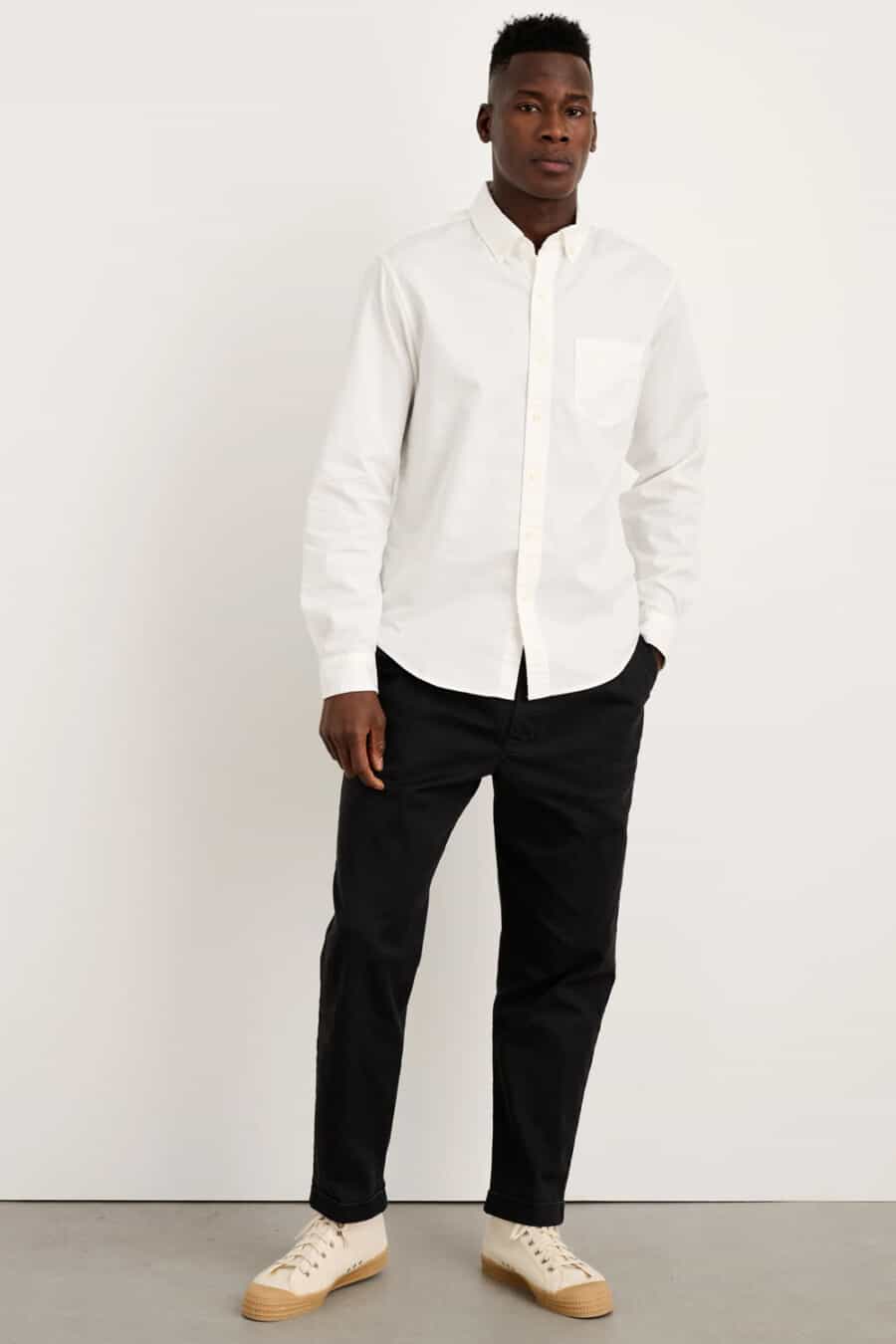 Men's black pants, white Oxford shirt and cream canvas high top sneakers outfit