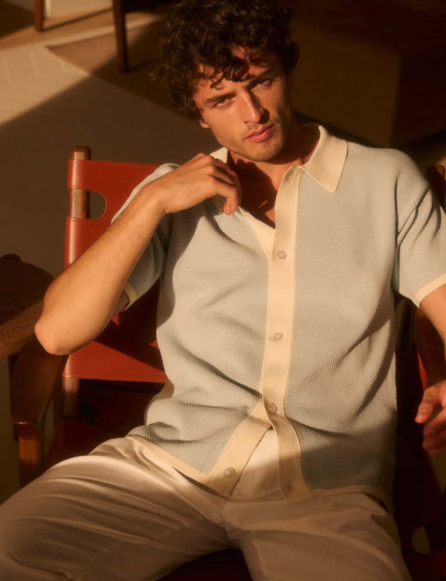 Man wearing a knitted light blue short sleeve summer shirt with white pants