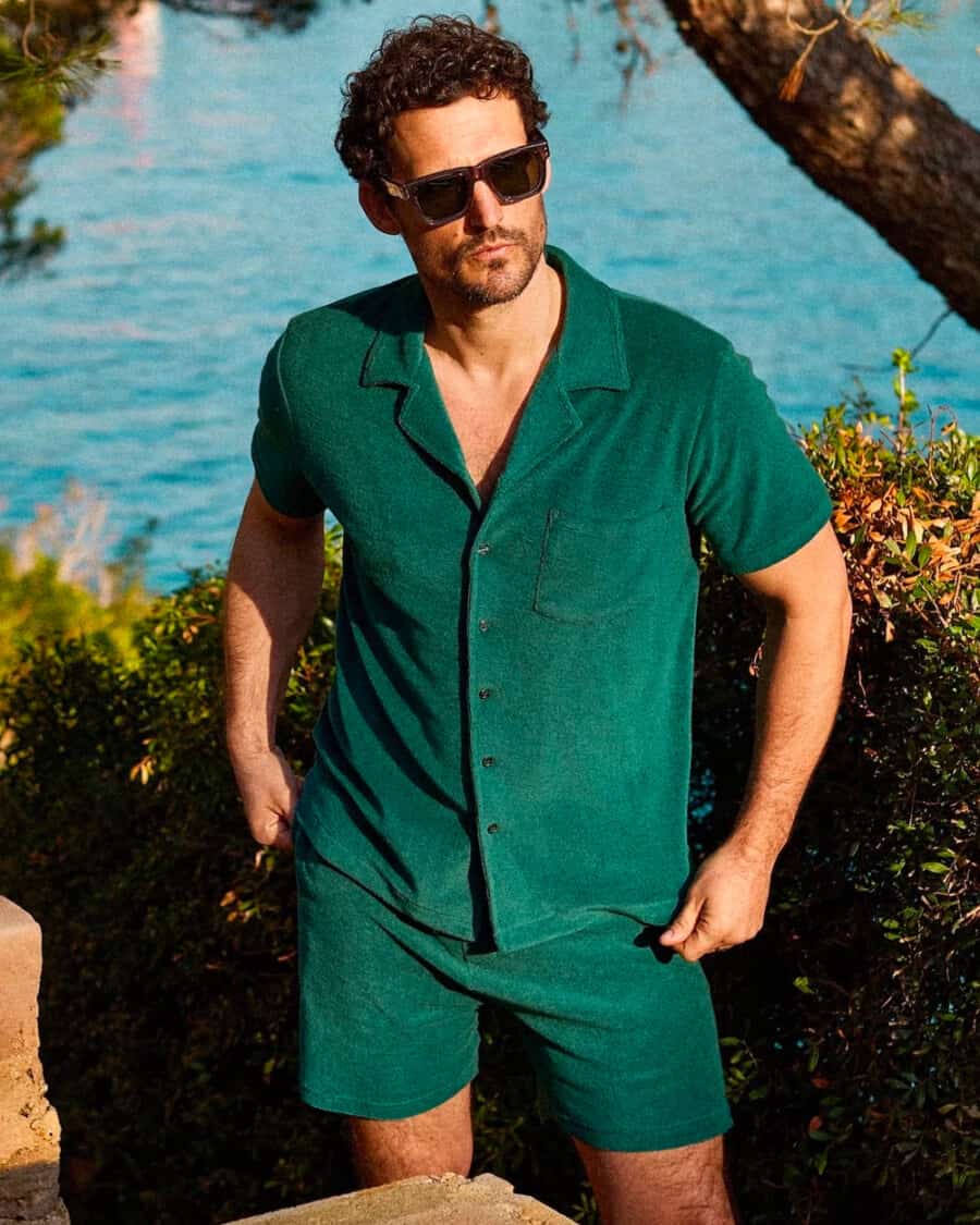 Man wearing a matching green Camp collar terry cloth shirt and shorts set with sunglasses on vacation