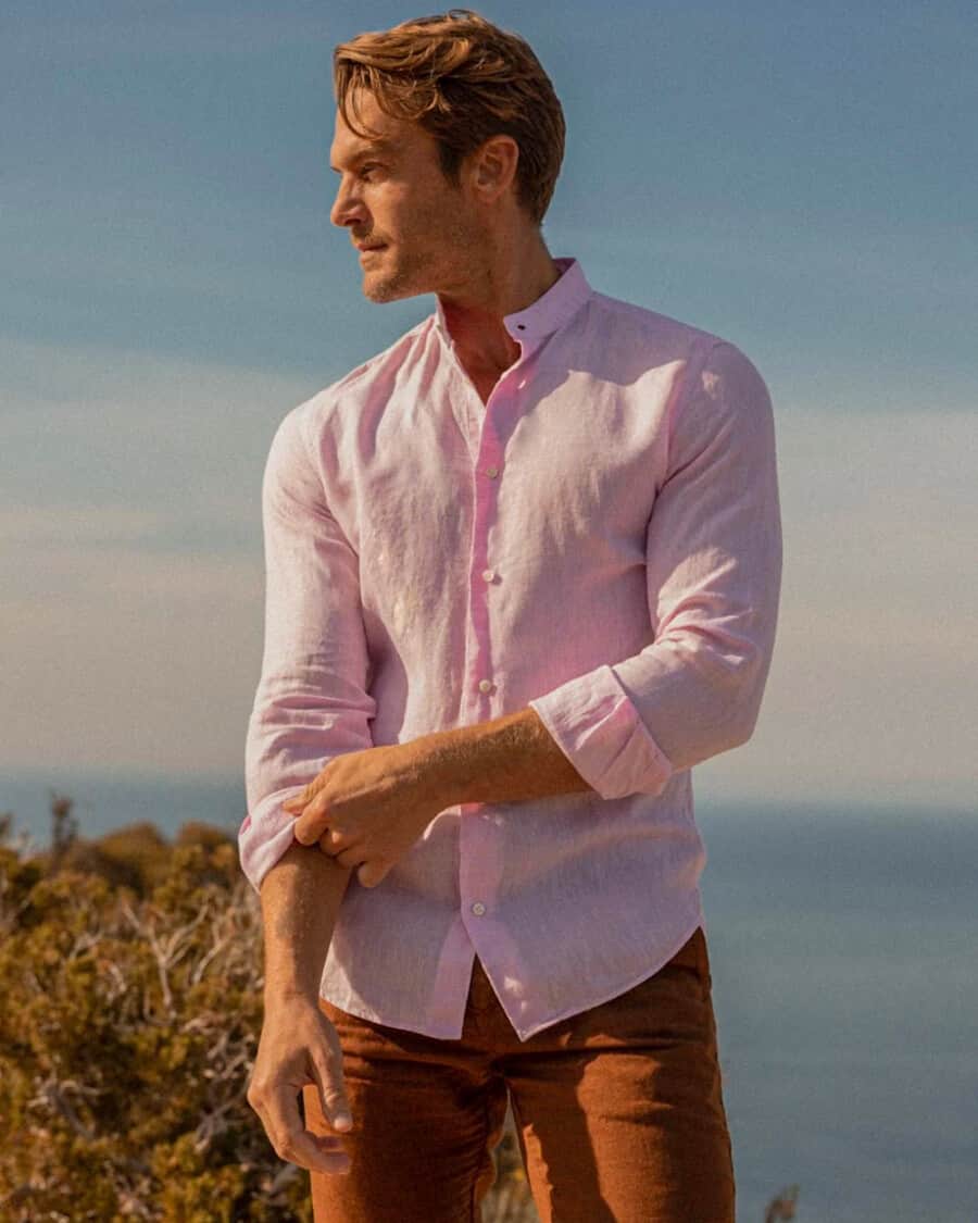 Man wearing a pink long sleeve linen shirt in summer with orange pants