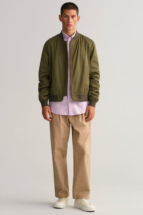 Men's loose khaki pants, pink oxford shirt, green bomber jacket and white sneakers outfit