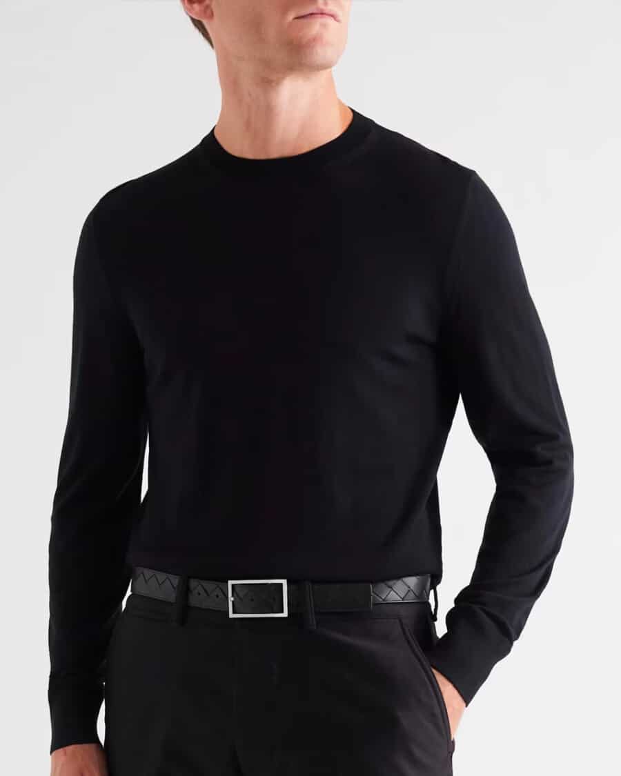 Man wearing black pants, black knit sweater and luxury black leather belt by Bottega Veneta