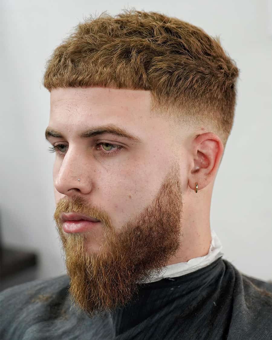 Men's textured ginger Caesar haircut with low taper fade and long beard