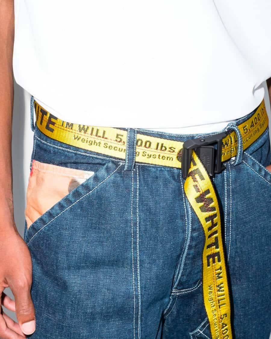 Man wearing utility jeans, white T-shirt and long Off-White yellow tape belt