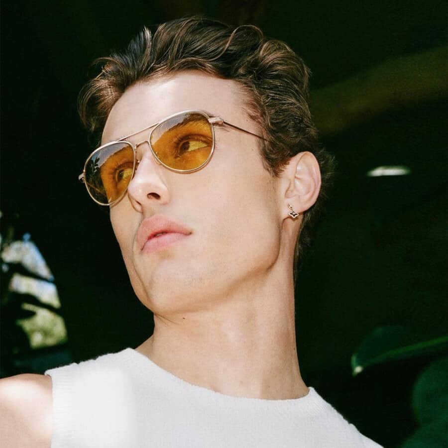 Man wearing metal frame aviator sunglasses with tinted orange lenses and a white tank top