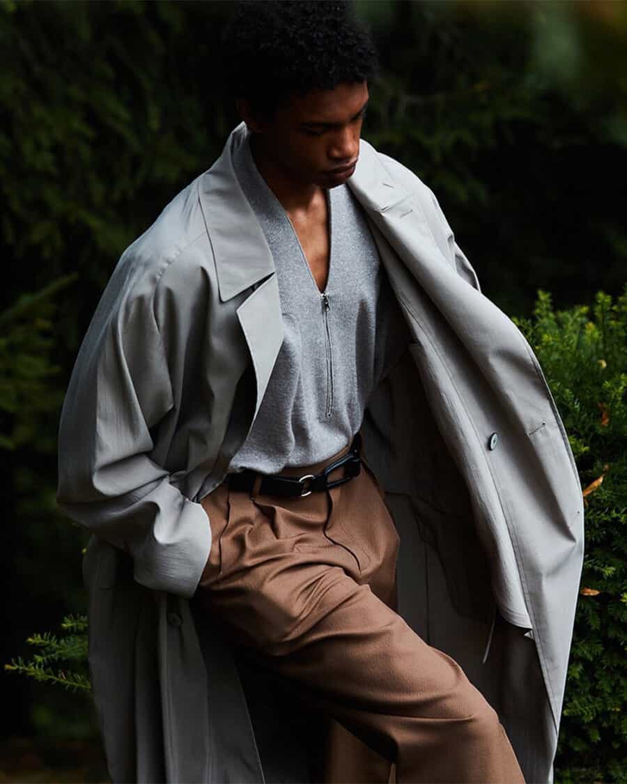 Man wearing khaki pants, grey zip top, grey mac coat and luxury black leather Zegna belt