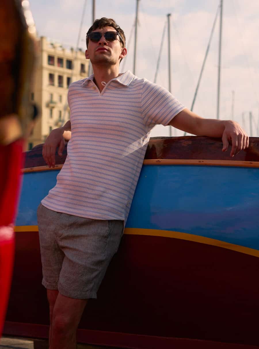 Man wearing a knitted striped Oliver Spencer polo shirt with grey fine vertical stripe shorts