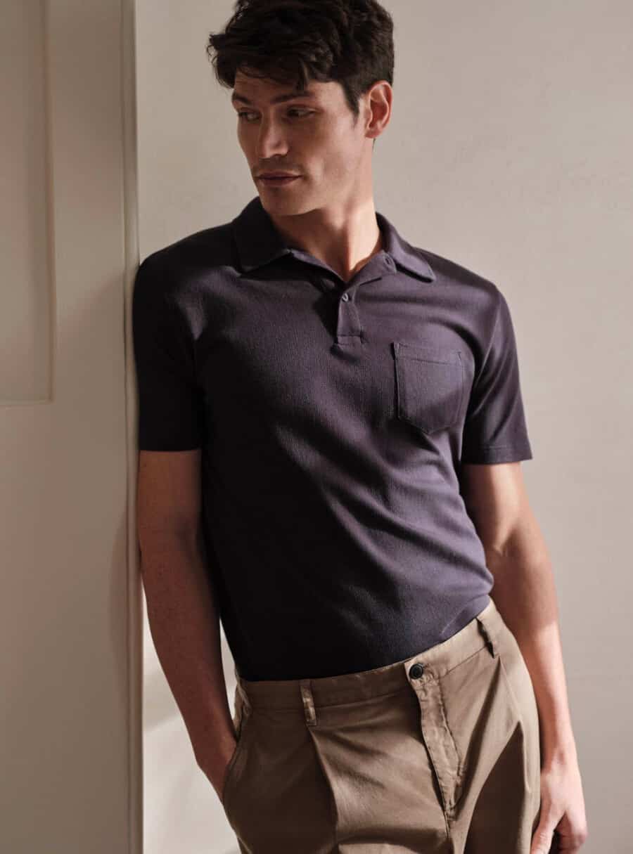 Man wearing a black luxury Sunspel polo shirt tucked into brown pants
