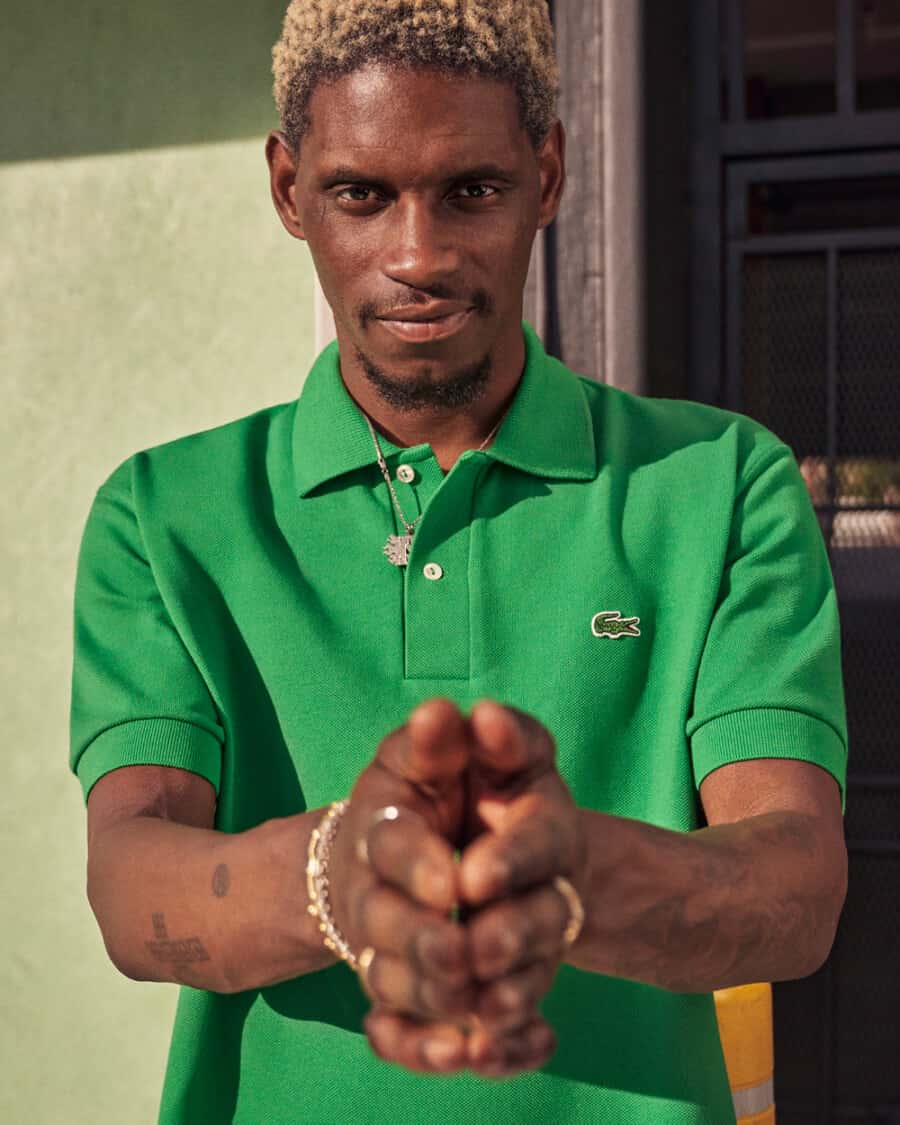 Black man wearing a bright green Lacoste branded polo shirt