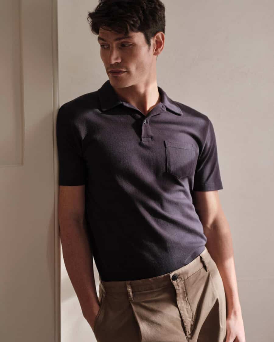 Man wearing high quality Sunspel black polo shirt tucked into brown pleated pants