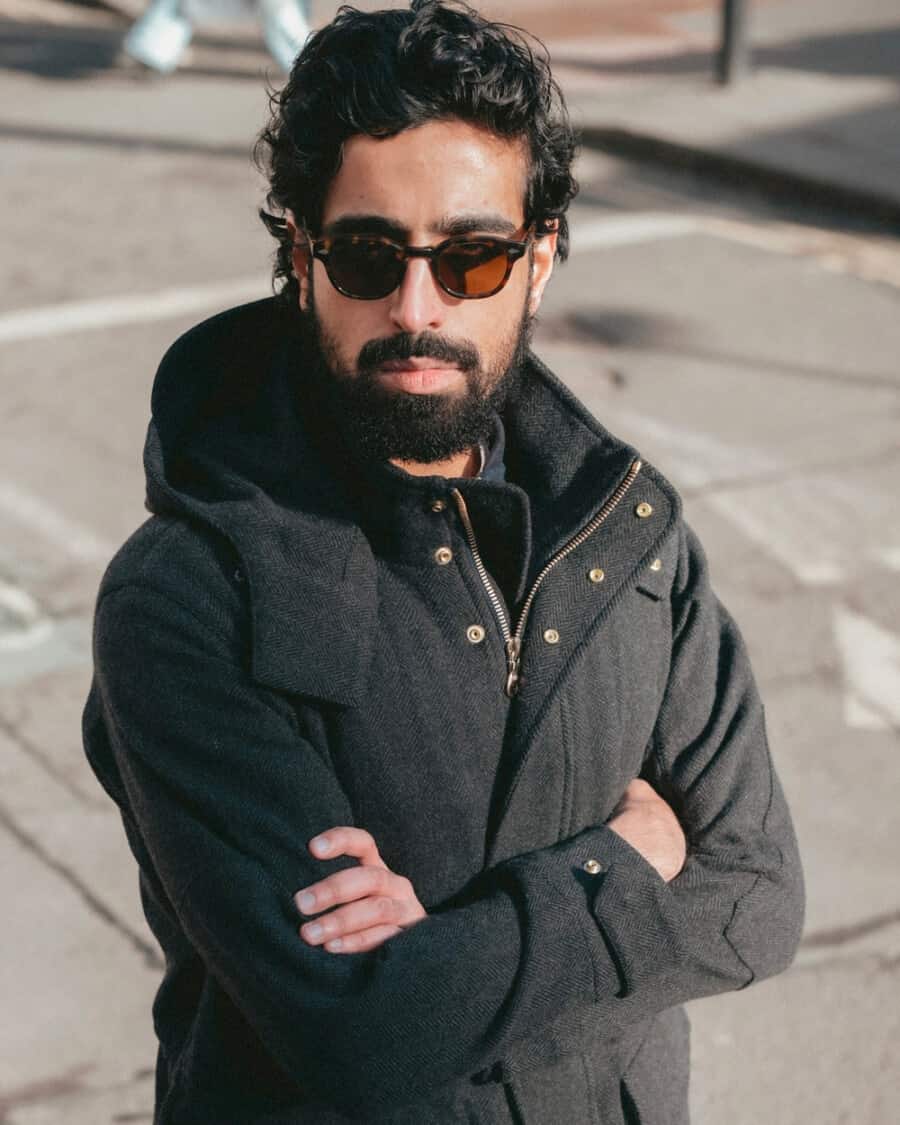 Man wearing a high quality charcoal wool parka jacket with black sunglasses