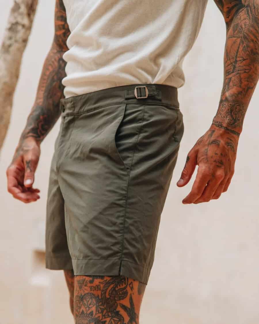 Man wearing green tailored swim shorts with a tucked in white T-shirt
