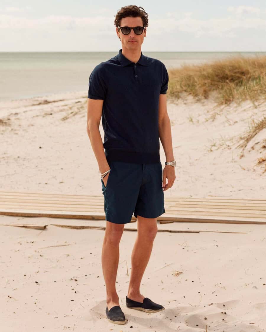 Man wearing tailored navy swim shorts with a knitted navy polo shirt and navy espadrilles