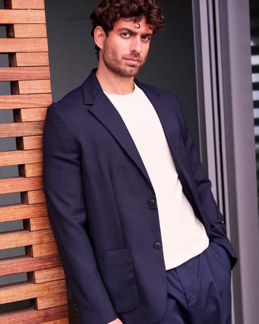 Man wearing an unstructured navy blazer with a white T-shirt and matching suit trousers