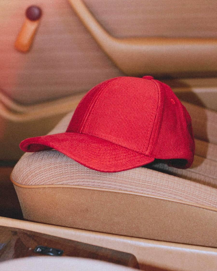 Red men's cord baseball cap on an upholstered car seat