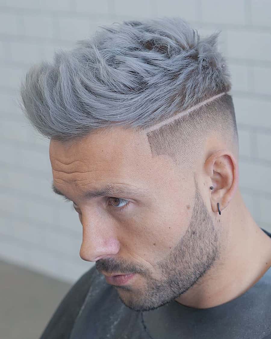 Man with dyed grey hair wearing faux hawk fade haircut with a shaved line design