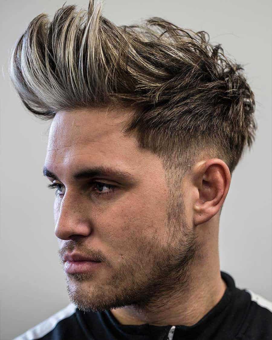 Man wearing a long, high, messy fohawk with tapered fade sides and blonde highlights
