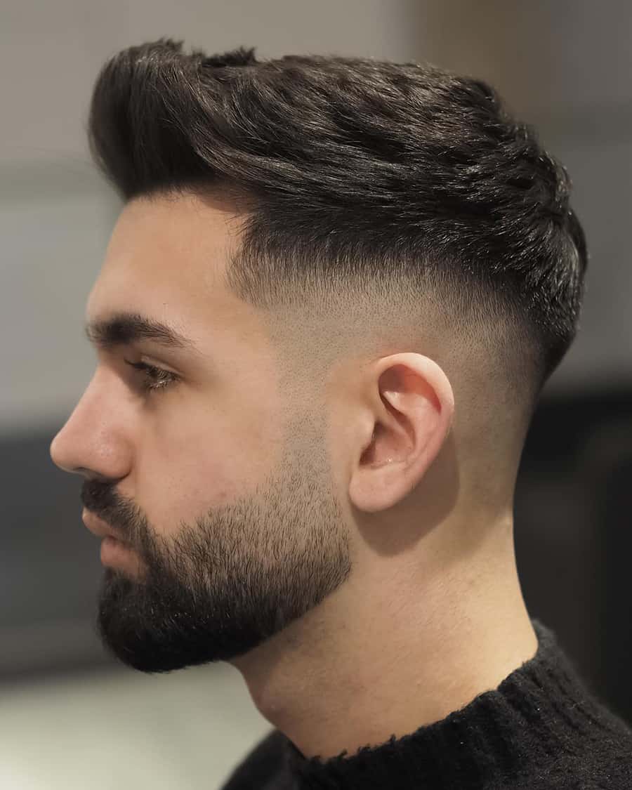 Man wearing a thick black faux hawk hairstyle with a high skin fade
