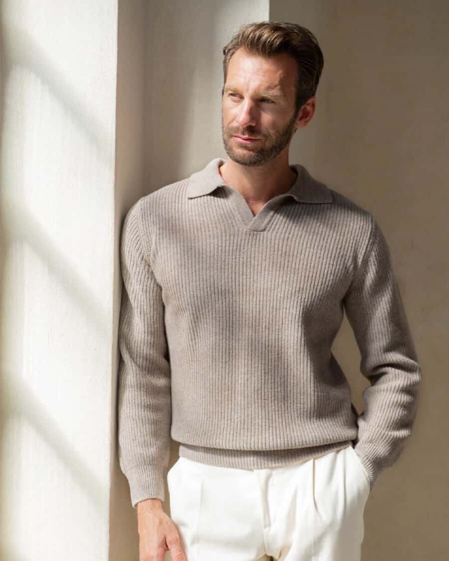Man wearing a luxury Pini Parma cashmere long-sleeve taupe polo shirt with open collar and white pants