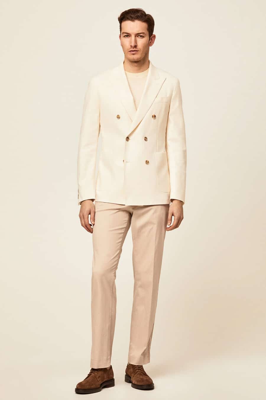 Men's khaki pants, cream T-shirt, cream double-breasted blazer and brown suede Derby shoes outfit