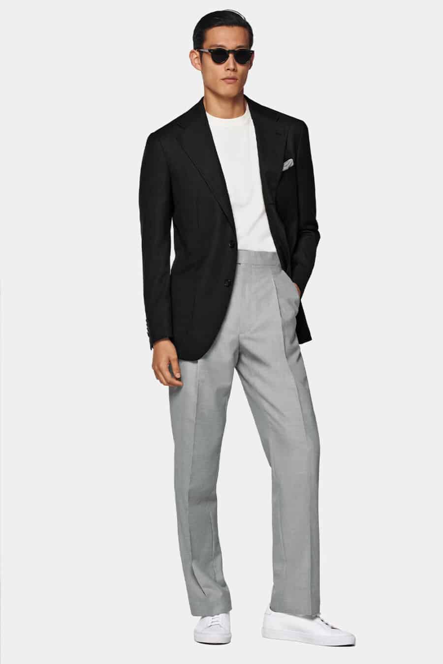 Men's light grey pants, white T-shirt, black blazer, round lens sunglasses and white sneakers outfit