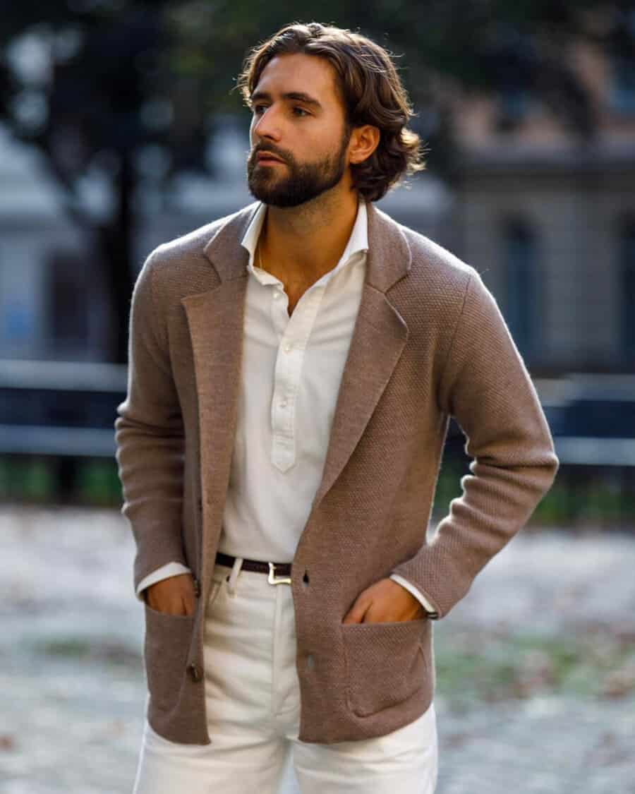 Man wearing white pants, white popover shirt, brown knitted unstructured blazer