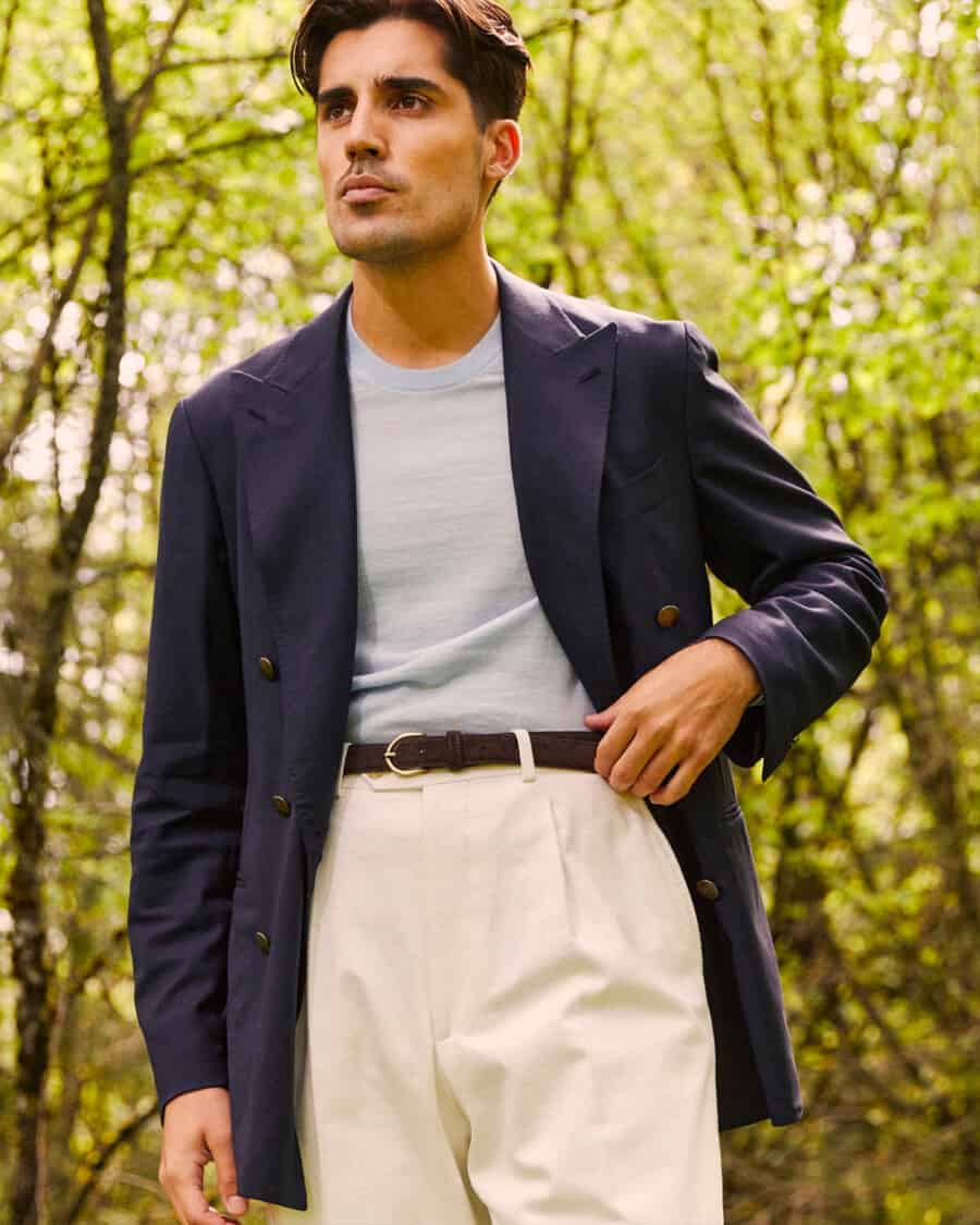 Man wearing white high-waisted pants, light blue T-shirt and unstructured navy blazer