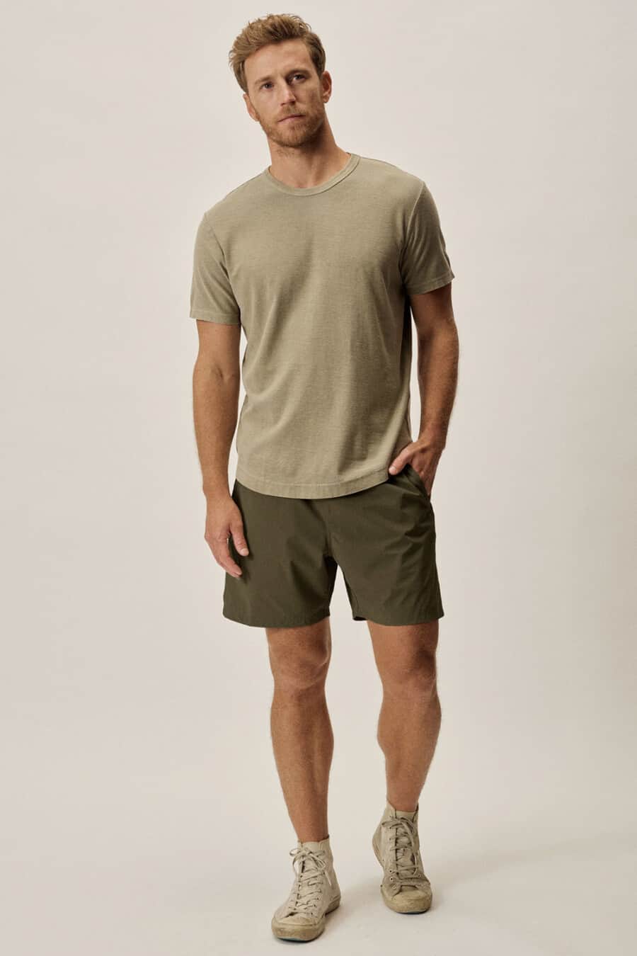Men's dark green shorts, olive green T-shirt and canvas high-top sneakers outfit