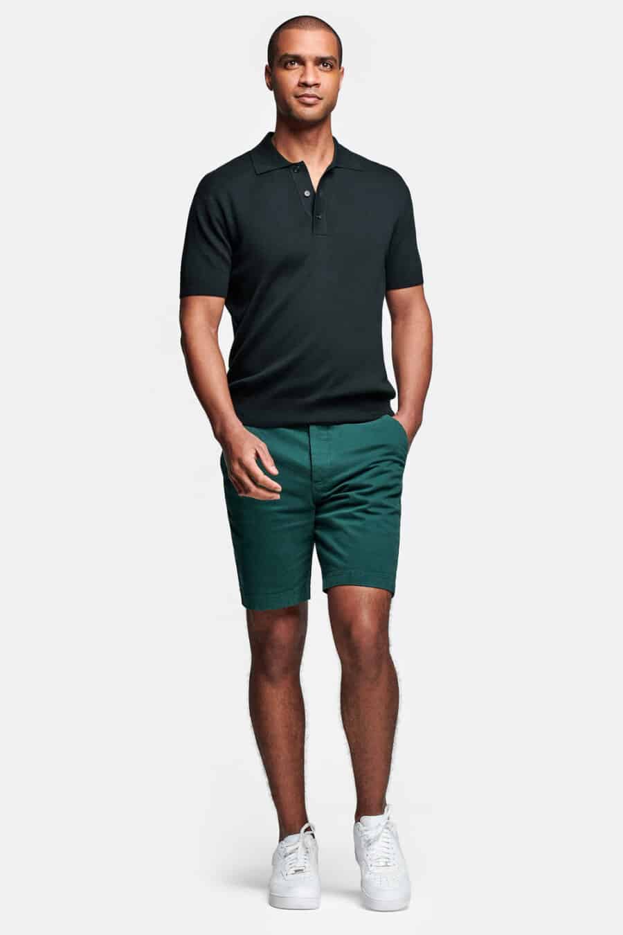 Men's teal green chino shorts, black polo shirt and white sneakers outfit