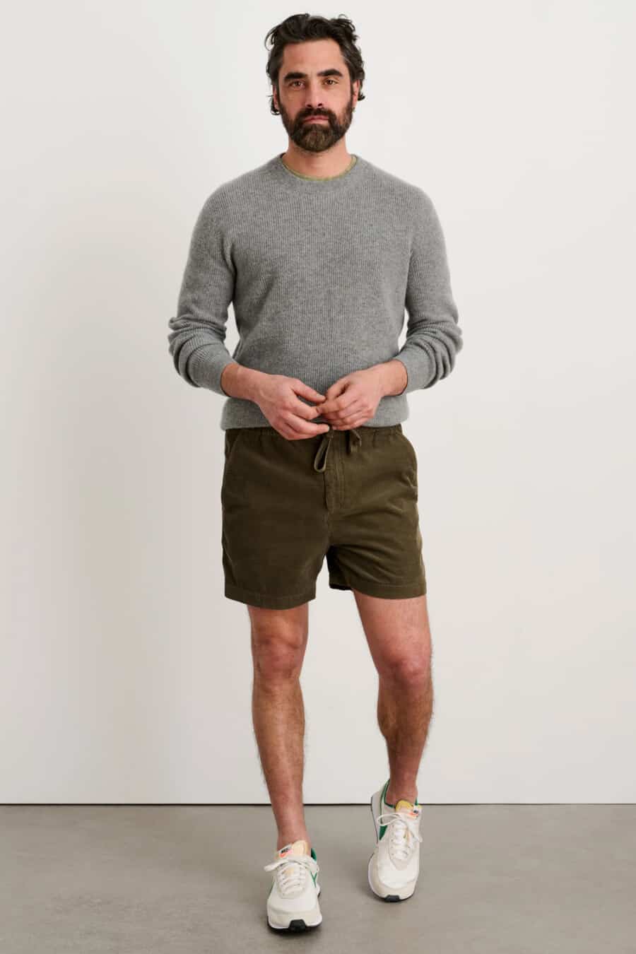Men's dark green drawstring shorts, grey crew neck sweater and white sneakers outfit