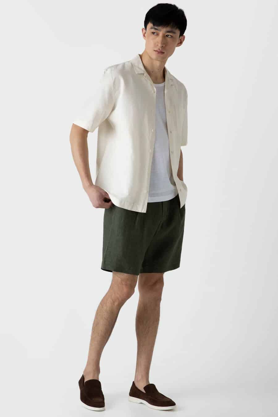 Men's dark green shorts, white vest, beige short sleeve shirt and brown suede loafers outfit
