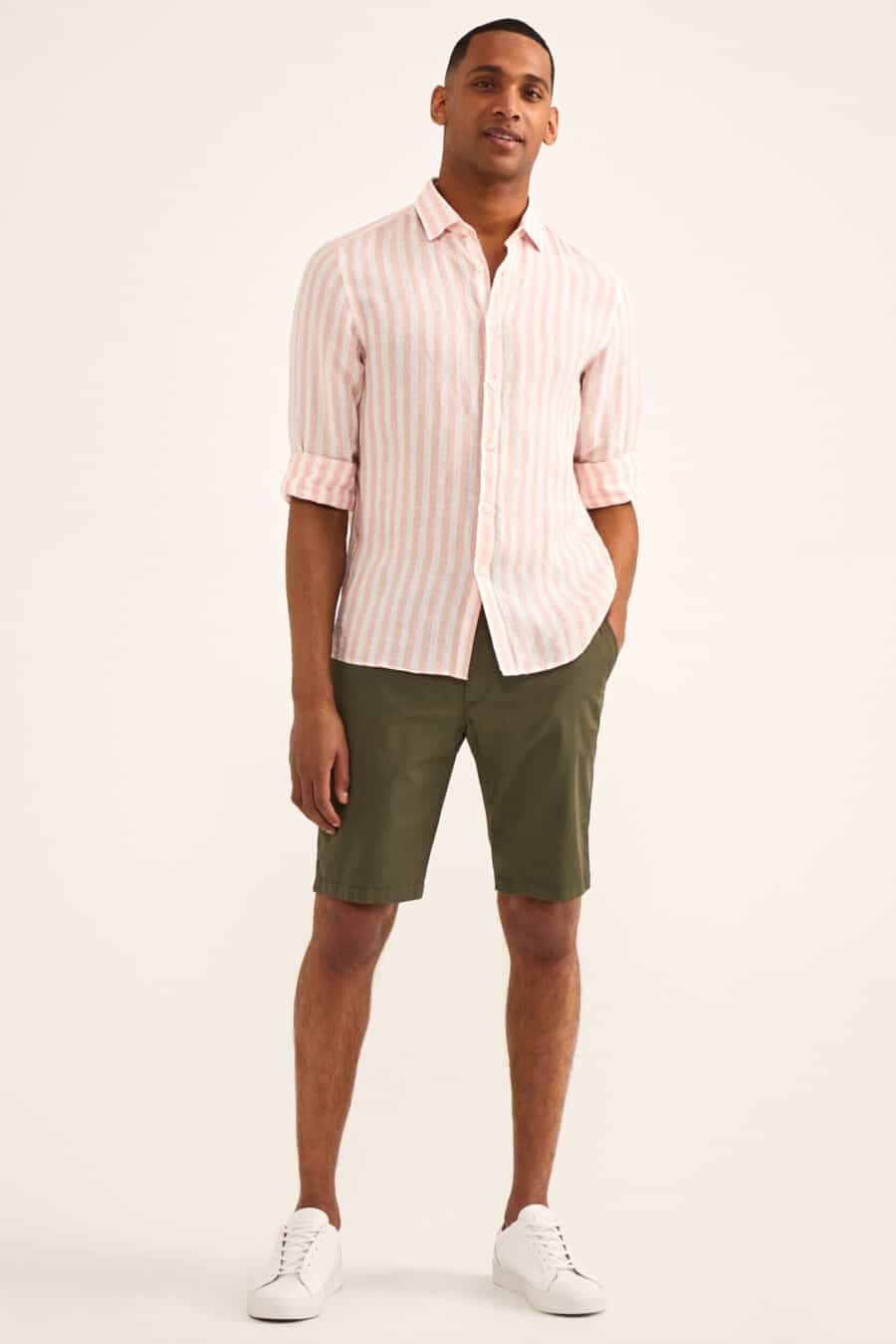 Men's dark green shorts, light pink striped shirt and white sneakers outfit
