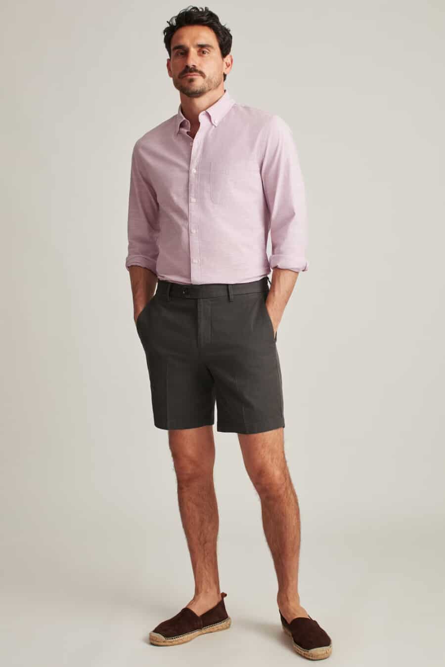 Men's pink button-down shirt tucked into charcoal grey tailored shorts with brown suede espadrilles outfit