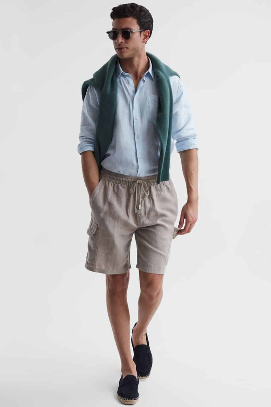 Men's grey cargo shorts, blue Oxford shirt, green sweater and navy espadrilles outfit
