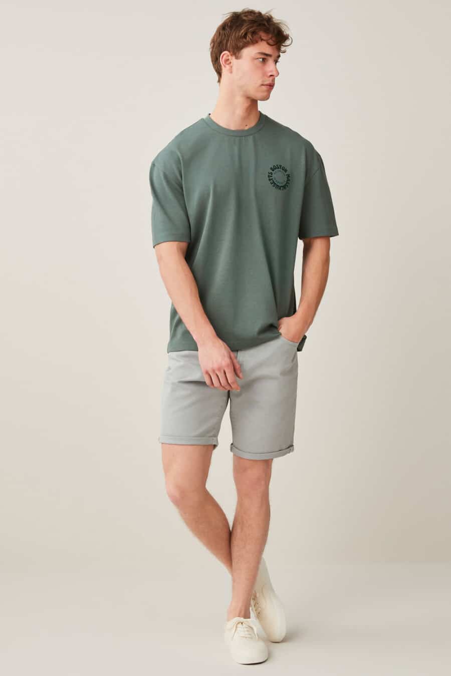 Men's grey shorts, green T-shirt and off-white canvas sneakers outfit