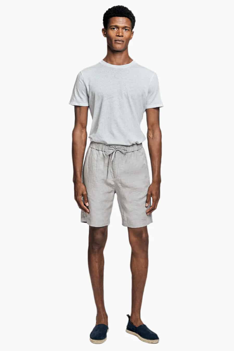 Men's light grey linen shorts with white T-shirt tucked in and navy espadrilles outfit