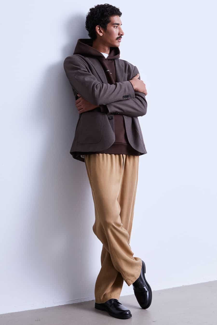 Men's loose khaki pants, brown hoodie, brown blazer and black Derby shoes outfit