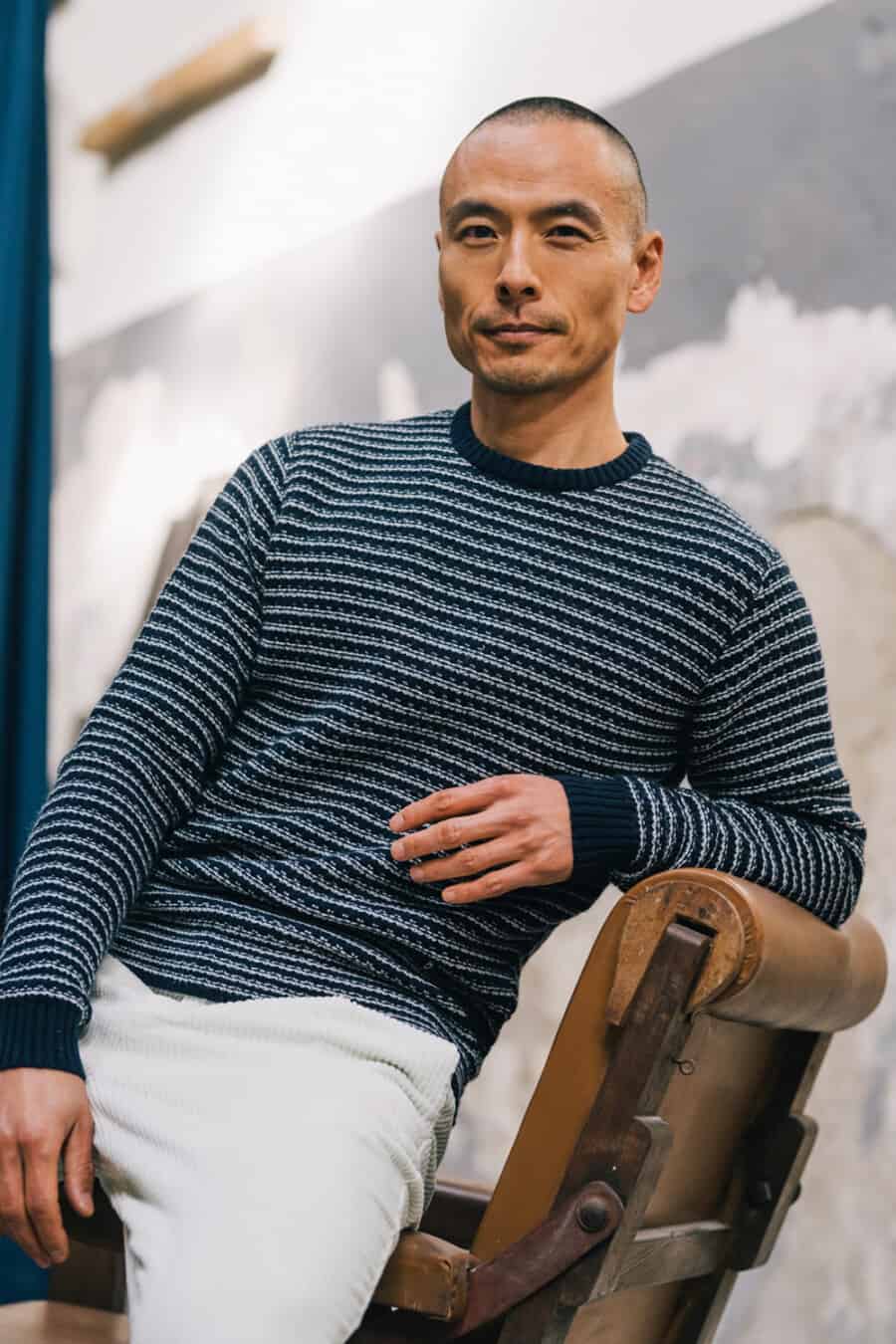 Man wearing white cord pants and blue/white waffle knit sweater