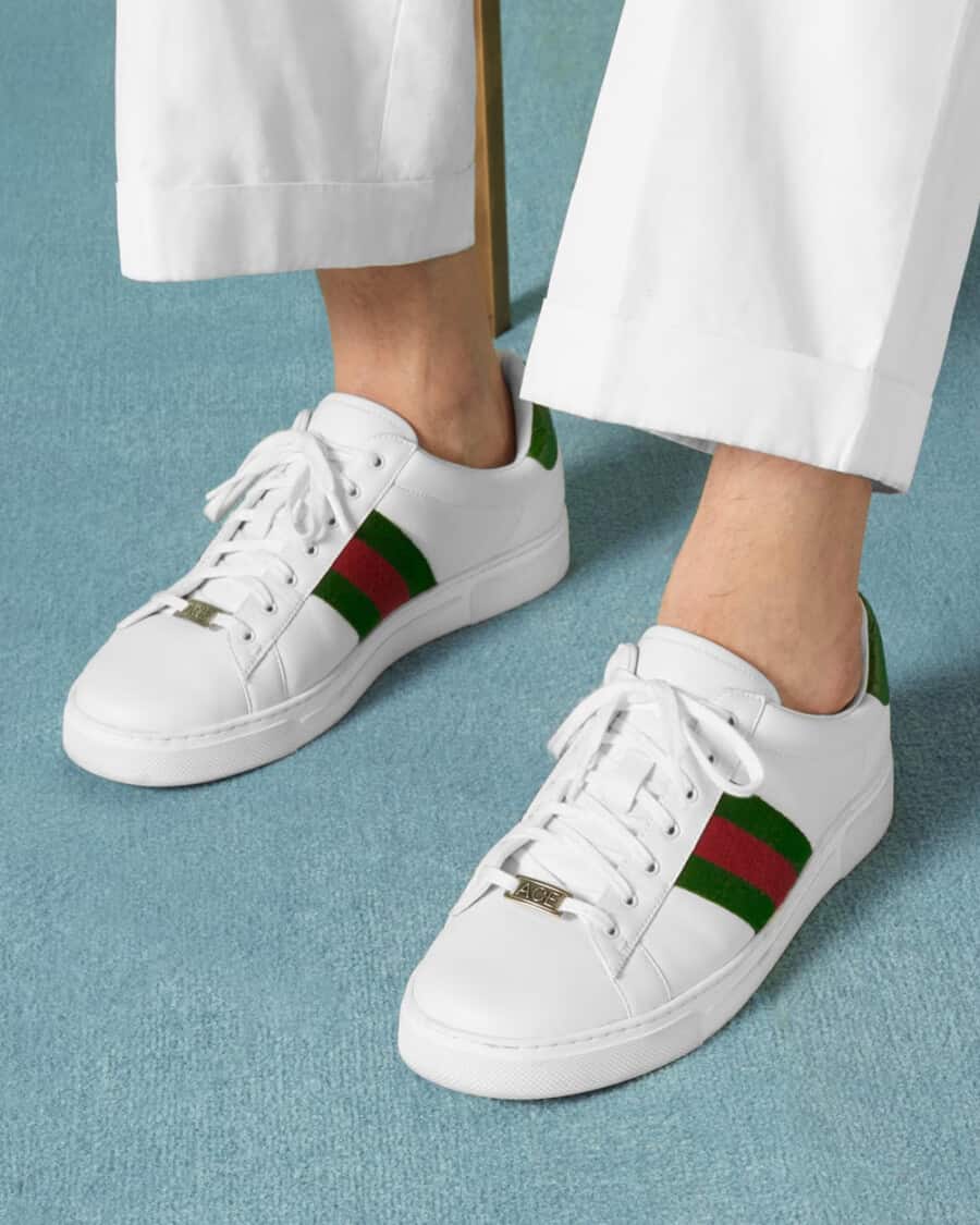 Men's Gucci Ace sneakers worn on feet with no socks and white pants