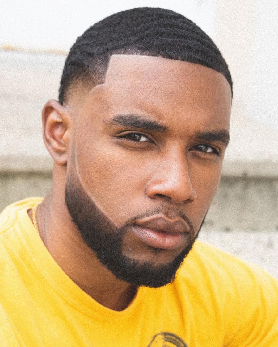 Black man with a buzz cut and waves and low skin fade
