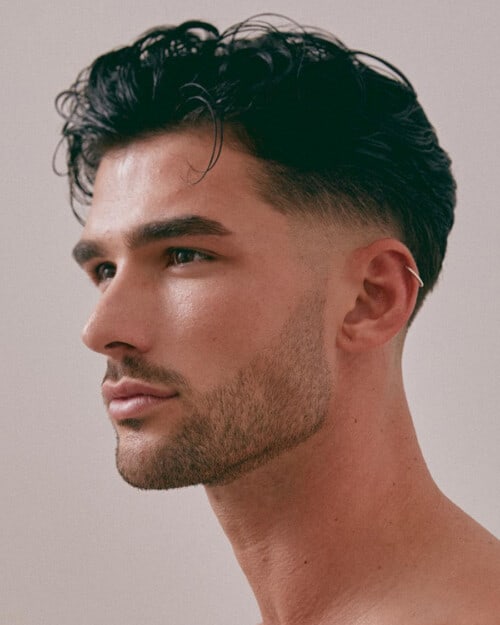 Men's wet-look medium length hair with low skin fade