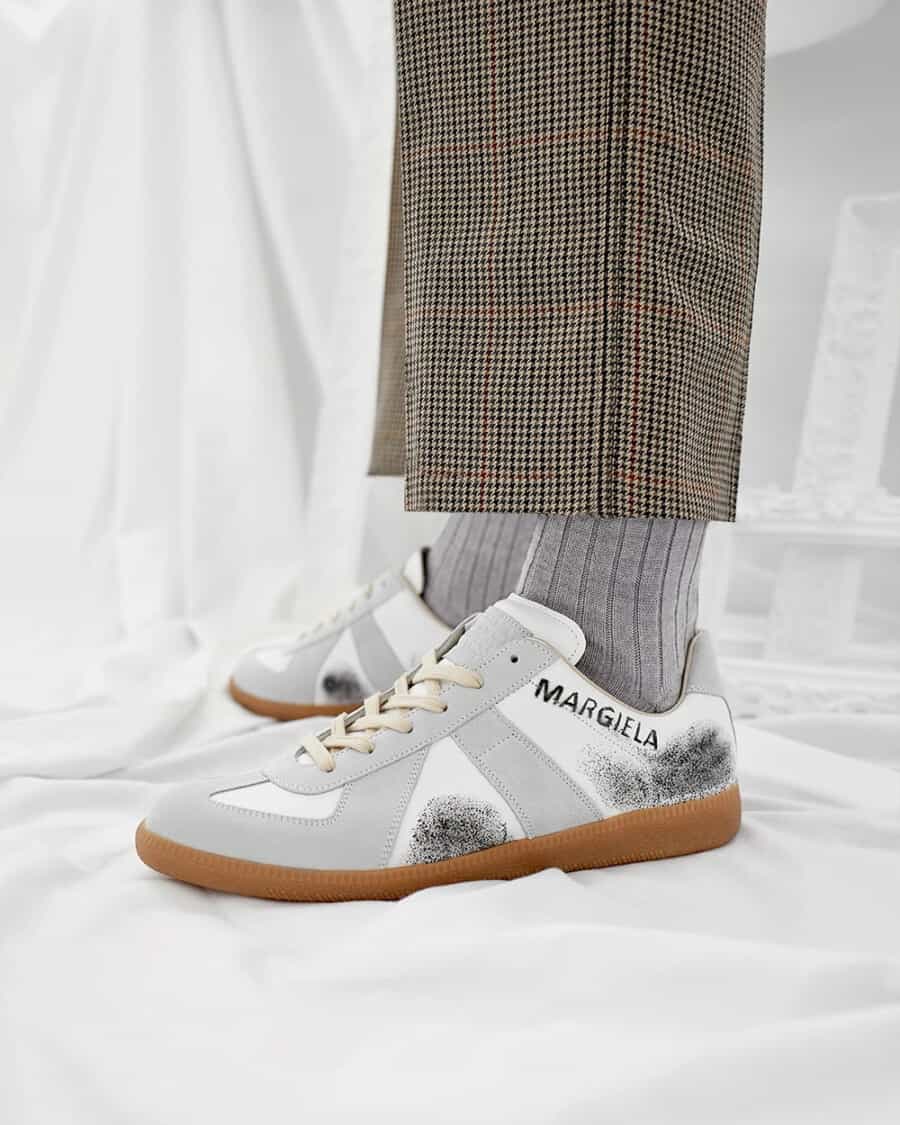 Men's Maison Margiela Replica sneakers worn on feet with grey socks and tailored mini check pants