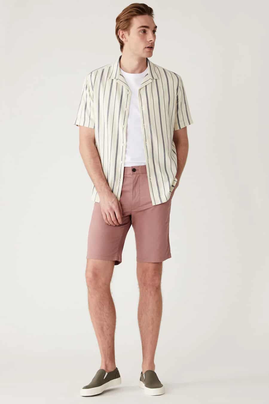 Men's pink chino shorts, white T-shirt, stripe beige short sleeve shirt and green suede slip on sneakers outfit