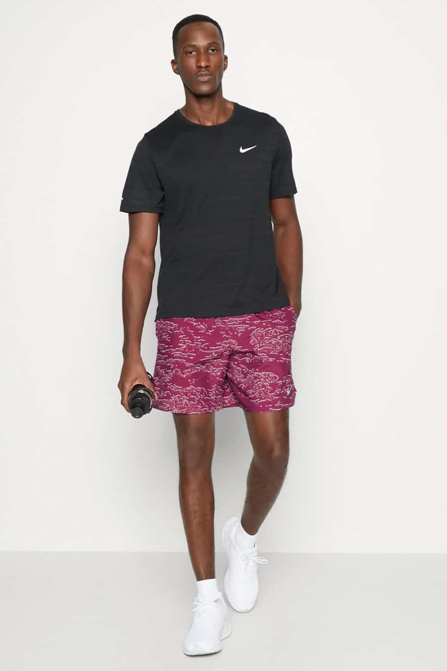 Men's patterned pink shorts, black Nike T-shirt, white socks and white running sneakers outfit