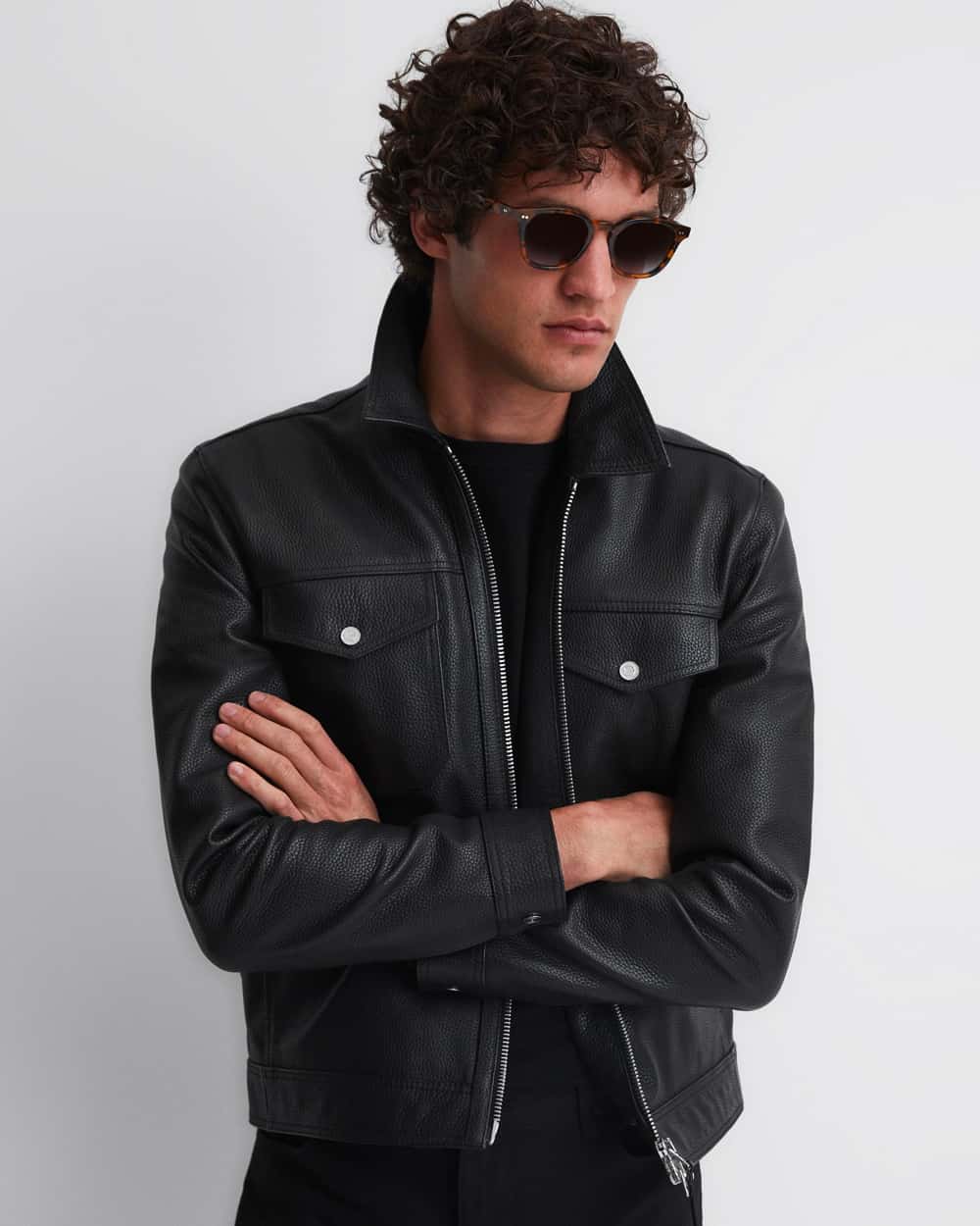 Man wearing Reiss black leather collared jacket with black sweatshirt, black pants and black sunglasses