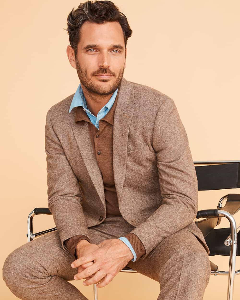 Man wearing a J.Crew Factory brown wool suit with a chambray light blue shirt and brown knitted long-sleeve polo shirt