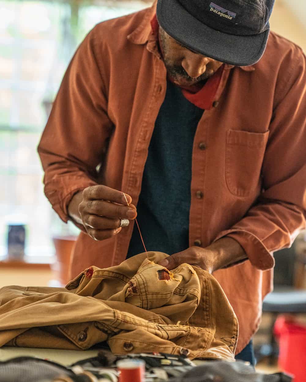 Man restitching/fixing a Patagonia garment