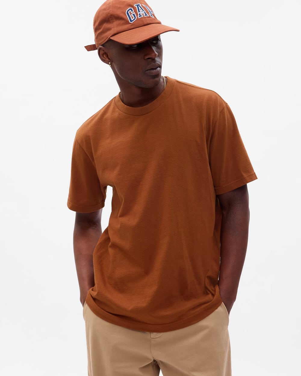 Man wearing a GAP brown T-shirt with khaki pants and a brown logo baseball cap
